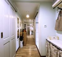 A hallway with a wooden decor floor in a 2-room apartment, with a coat rack wall and a cabinet.
