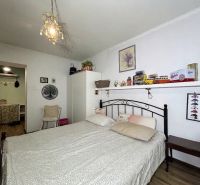 Bedroom in a 2-room apartment with a bed, decorations, and a floor with a wooden decor.