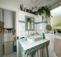 A bathroom in a 2-room apartment with white tiles and green decorations.