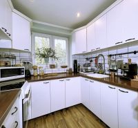 A kitchen in a 2-room apartment with white cabinets and a wood-patterned floor.