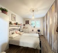 A bedroom in a two-room apartment with a wooden decor floor, curtains, and decorations.