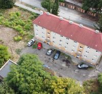 A building on Ľudovíta Štúra Street in Levice surrounded by greenery and a parking lot for cars.