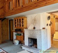The interior of a cabin with a fireplace, wooden staircase, and floor with a wooden decor.