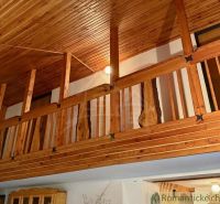 Wooden railing and ceiling with decor in the cottage create a cozy atmosphere.
