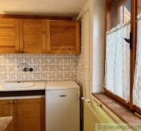 Rustic kitchen in a cottage with wooden decor and decorative tiles.