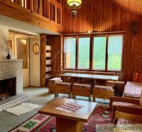 A cottage with wooden paneling, a fireplace, and textiles with folk motifs.