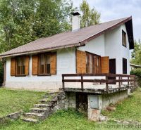 A cottage in Košická Belá with a stone staircase and wooden shutters in a natural setting.