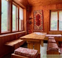 Interior of a cabin with wooden paneling, a carpet on the wall, and large windows.