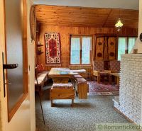 A cottage with wooden decor, carpet, and rustic wooden furniture, decorative carpet on the wall.