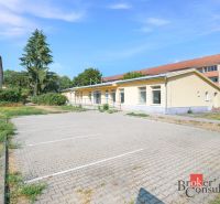Commercial premises on Š. Moysesa in Žiar nad Hronom, parking lot and yellow building.