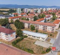 A view of commercial spaces in Žiar nad Hronom on Š. Moysesa with apartment buildings and a panorama.