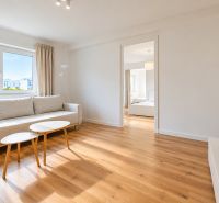 Living room in a 2-room apartment with a sofa, tables, and a floor with a wooden decor.