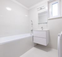 A bathroom in a 2-room apartment with a bathtub, a white sink, and a washing machine.