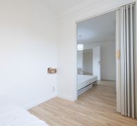 Interior of a 2-room apartment with a wooden decor floor and sliding doors.