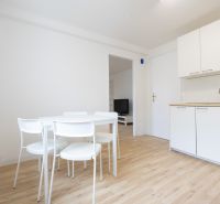 Dining area with a white table and chairs in a 2-room apartment, floor with wood decor.