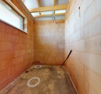 Unplastered bricks and a window in the interior of a family house awaiting completion.