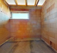 Unfinished room in a family house with brick walls and a small window.