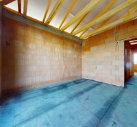 A room with bare brick walls and exposed rafters in a family house.