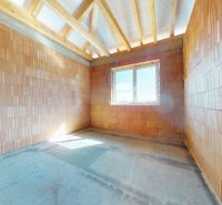 Unfinished interior of a family house with brick walls and a window.