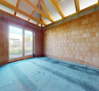 A room in a family house with raw brick walls and a window to the garden.