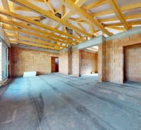 Unfinished interior part of a family house with visible wooden beams and brick walls.