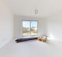 An unfurnished room with a large window in a family house, materials spread out on the floor.
