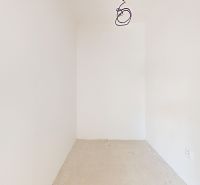 An empty room in a family house with white walls and an unfinished floor.