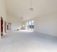A spacious room in a family house with large windows and an unfinished floor.