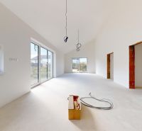 Spacious room in a family house with large glass doors and an unfinished ceiling.