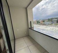 A balcony with tiles overlooking the city from a studio apartment.