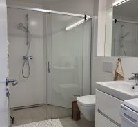 Bathroom with a shower, sink, and washing machine in a studio apartment.
