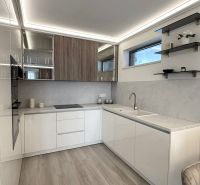 Kitchen in a 2-room apartment with white cabinets and a wood-patterned floor.