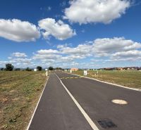 Nová Dedinka, Bernolákova, empty plot, flat road, blue sky, only a few houses.
