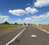 The road on Bernolákova Street in Nová Dedinka surrounded by meadows and a sky with clouds.