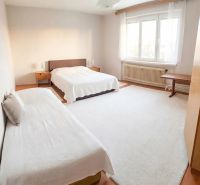 Bright bedroom interior in a family house with wood-decor flooring and comfortable beds.