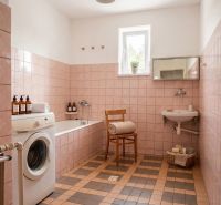 A bathroom in a family house with beige tiles, a bathtub, and a washing machine.