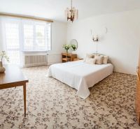 A bedroom in a family house with a floral carpet, a double bed, and wooden furniture.