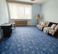 Living room in a family house with a blue carpet and simple furnishings.
