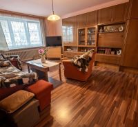 Living room in a family house with wood-patterned flooring, a sofa set, and cabinet furniture.