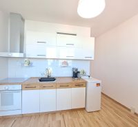 A kitchen in a 3-room apartment with white cabinets and a wooden decor floor.