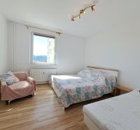 A bright bedroom in a three-room apartment with a window and a wooden decor floor.