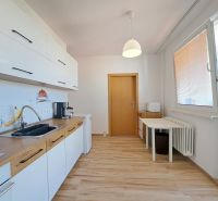 A kitchen in a 3-room apartment with a wooden decor floor and white cabinets.