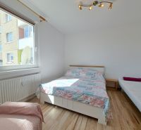A bright bedroom in a three-room apartment with beds and wood-decor flooring.
