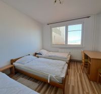 A bedroom with three beds and a table in a 3-room apartment, floor with wood decor.