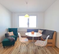 Dining room with an armchair, corner bench, table, and floor with wood decor in a 3-room apartment.