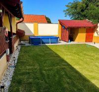 The garden of a family house in Darnózseli with a lawn and a swimming pool, surrounded by a fence.