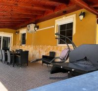 The terrace of a family house in Darnózseli with rattan furniture and a grill under a wooden ceiling.