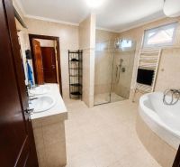 A bathroom in a family house with a double sink, shower, and bathtub.