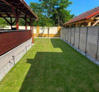 The garden of a family house in Darnózseli with a lawn, pergola, and surroundings of trees.