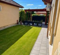 The garden of a family house in Darnózseli with a green lawn and a paved pathway.
